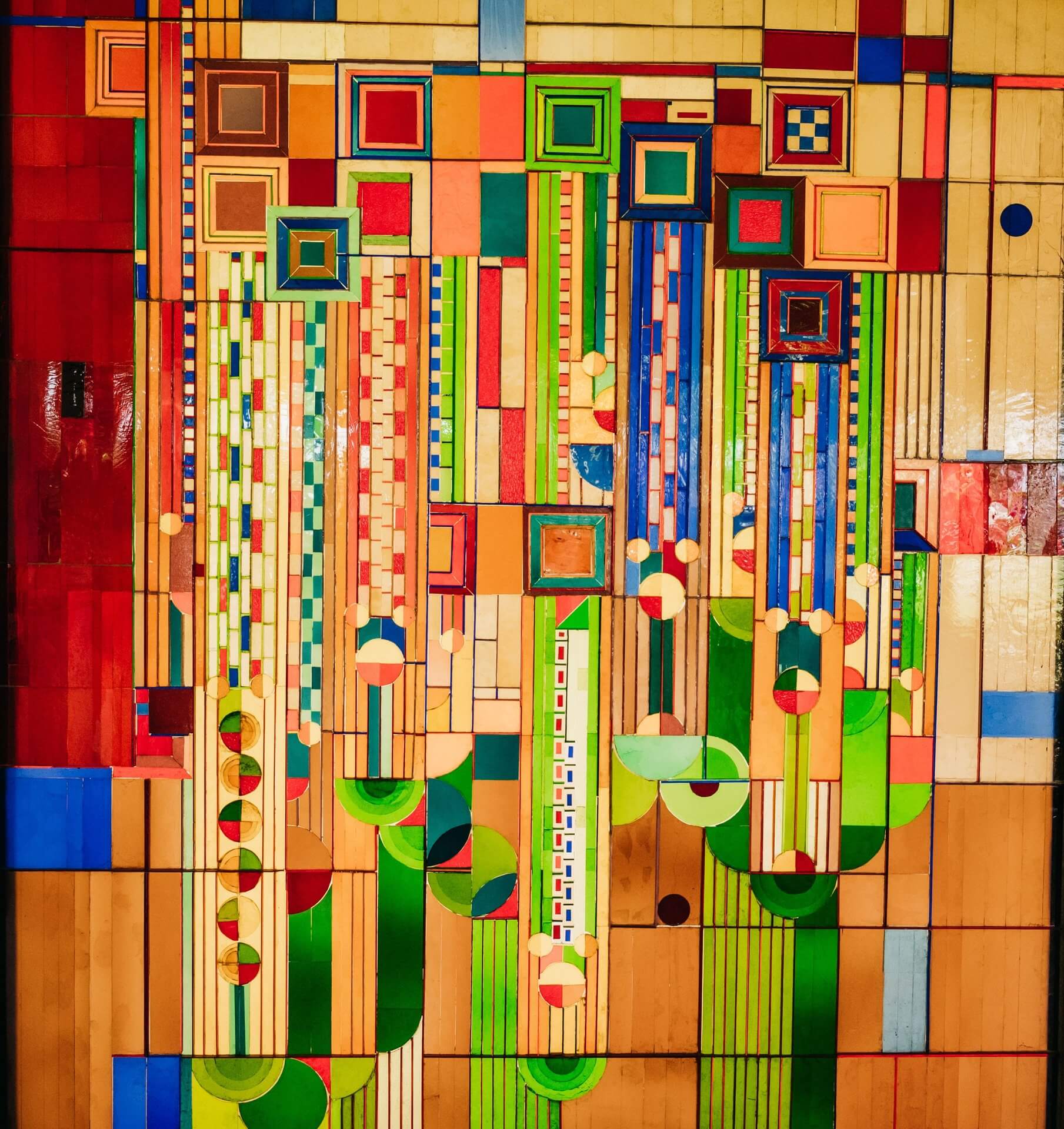 This vibrant abstract artwork is all about a mix of geometric shapes and patterns with vivid colors like red, green, blue, and yellow. The composition includes squares, rectangles, circles, and lines, creating a dynamic and visually engaging piece.
