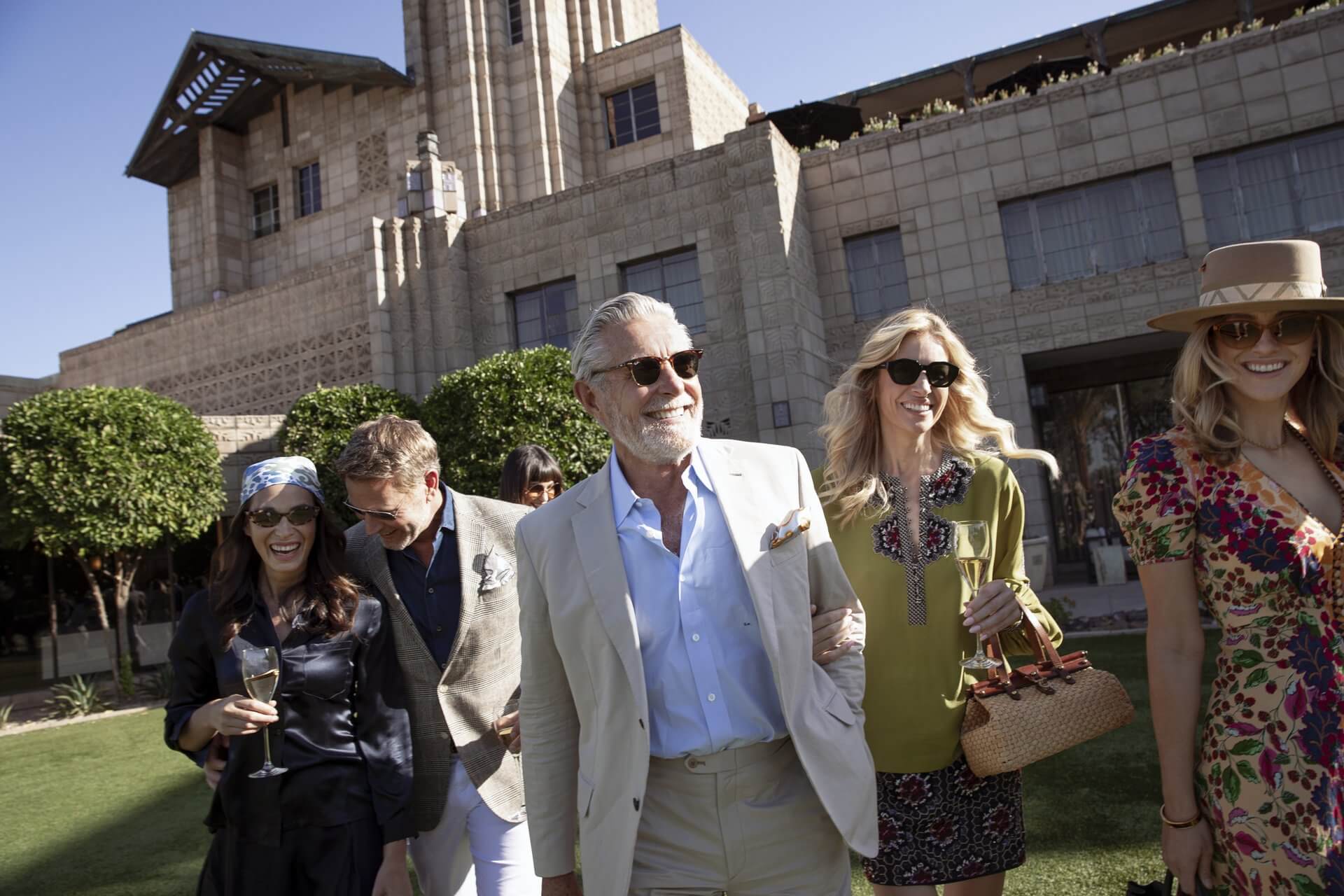 Groups of people in dapper attire on the front lawn of rhe Arizona Biltmore