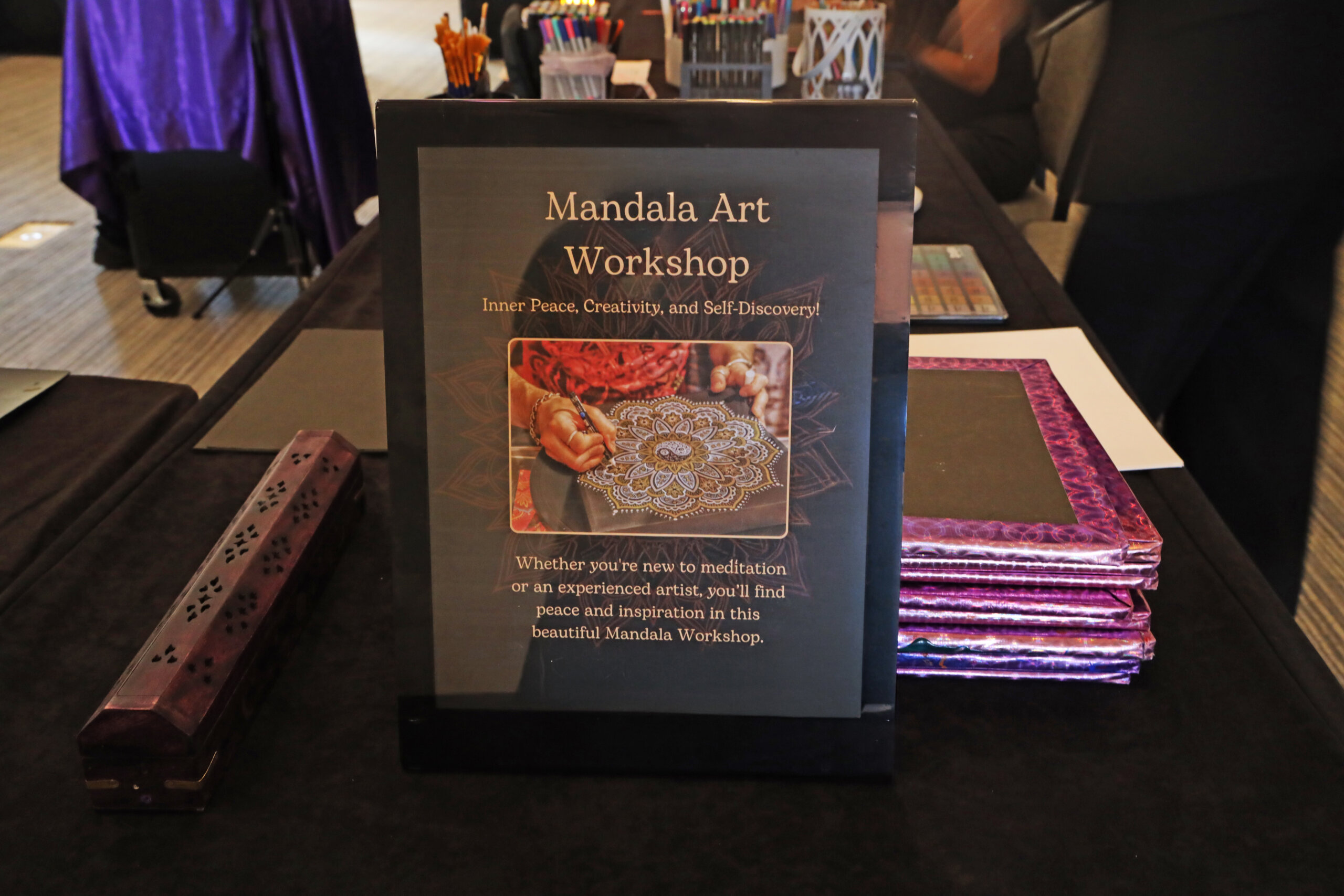 Sign for a Mandala Art Workshop with an image of a hand drawing a mandala, stating it is for inner peace, creativity, and self-discovery.